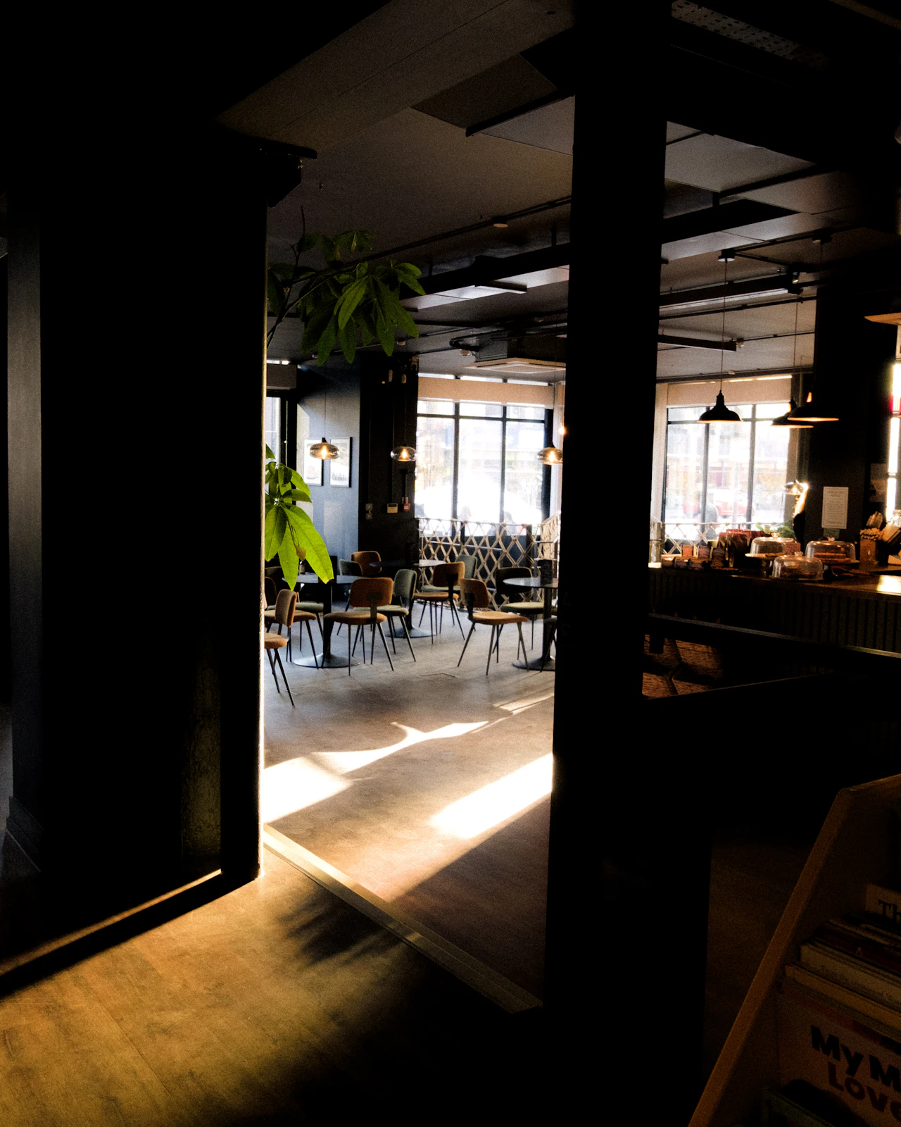 Warmes Sonnenlicht fällt durch die Fenster auf Tische und Stühle in einem ruhigen Café.